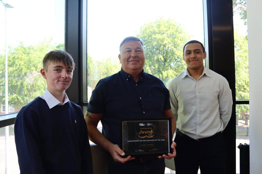 Three people at the apprenticeship awards lunch. One is holding his awards certificate.